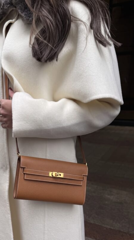 Model carrying the brown Epsom Herme$ Kelly Long Wallet To Go with its shoulder strap