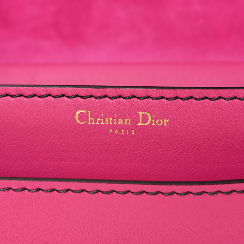 Close-up of the J’Adior logo and chain hardware on the fuchsia flap bag