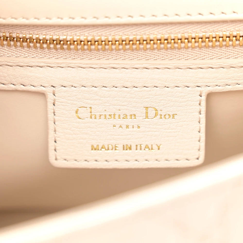 Close-up of the antique gold-tone CD twist clasp on the beige Caro bag