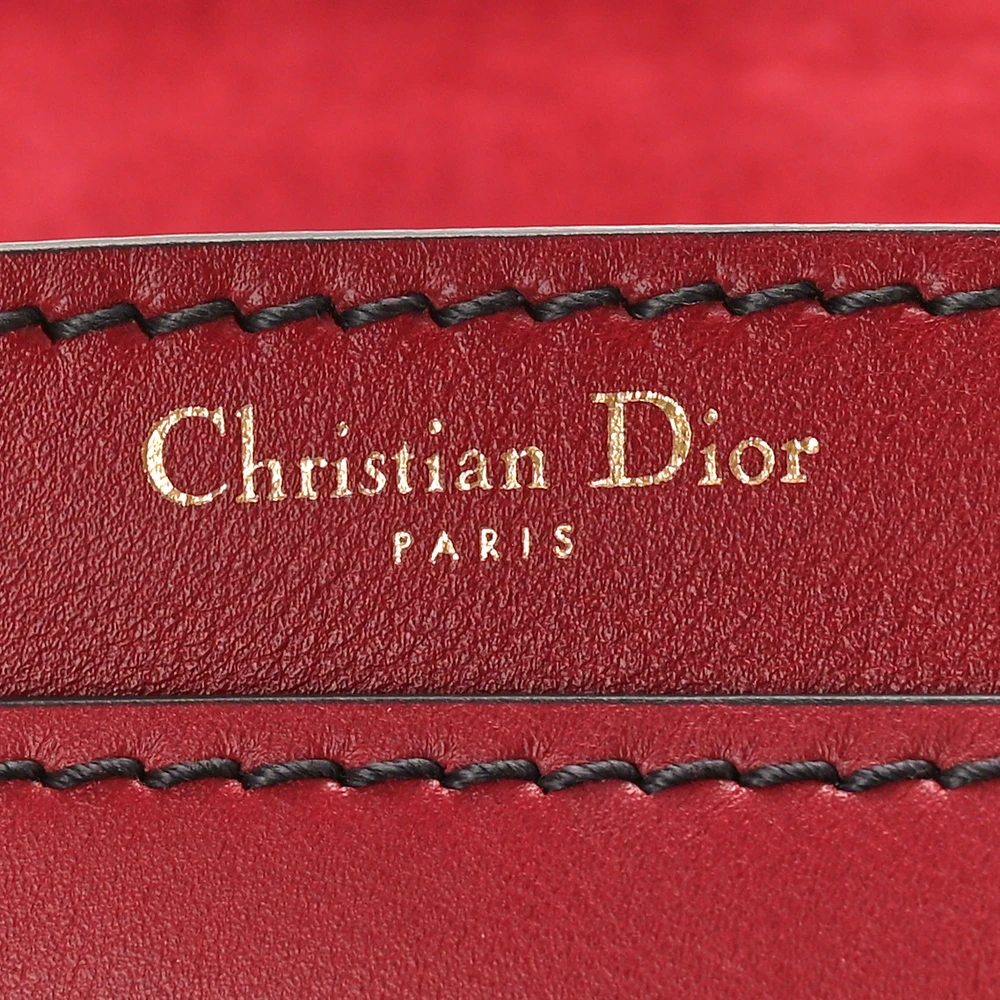 Close-up of the gold-tone J’ADIOR signature on the red D!0r J’Adior Chain Flap Bag