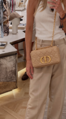Model carrying the Mirror Quality beige D!0r Caro shoulder bag