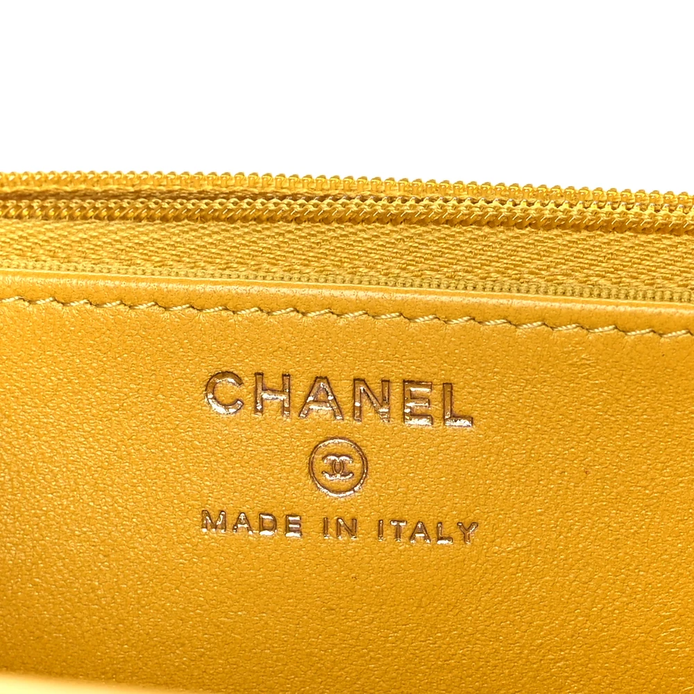 Close-up of the gold-tone CC detail and chain hardware on the yellow WOC bag