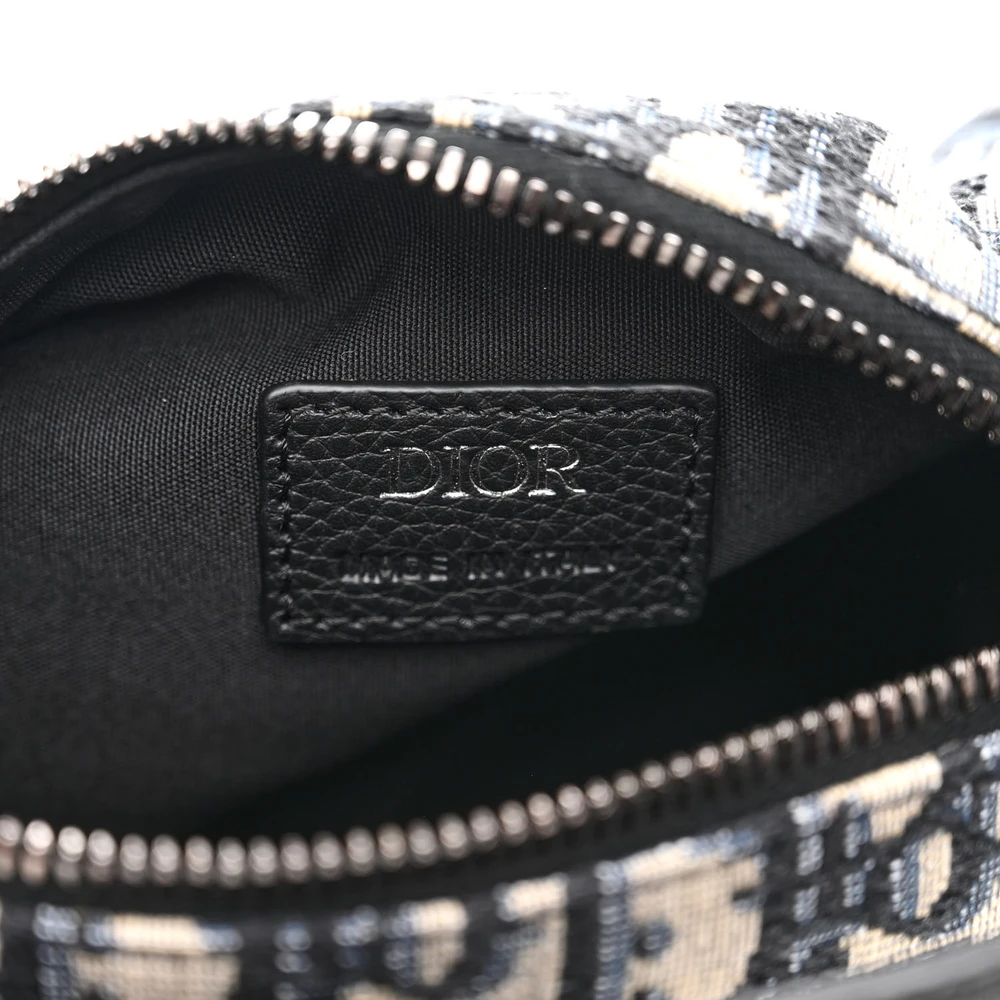 Close-up of the silver-tone hardware and logo canvas strap on the blue D!0r Mini Roller Messenger Bag