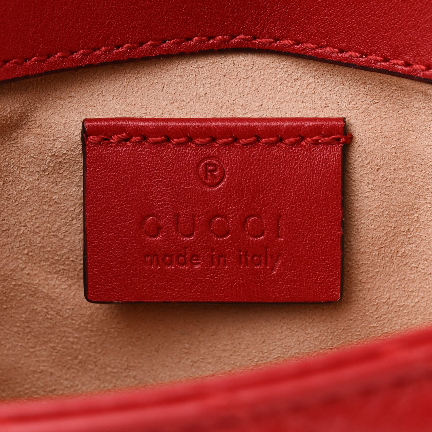 Close-up of the aged gold-tone interlocking GG logo on the red Gucc! Super Mini GG Marmont Bag