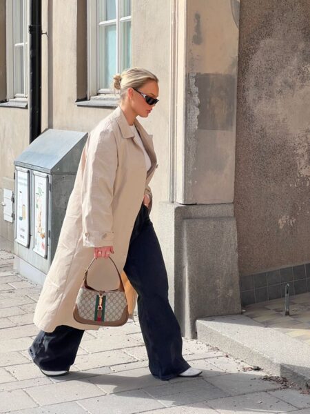 Model wearing the beige and white Gucc! Jackie 1961 Small Hobo with striped shoulder strap