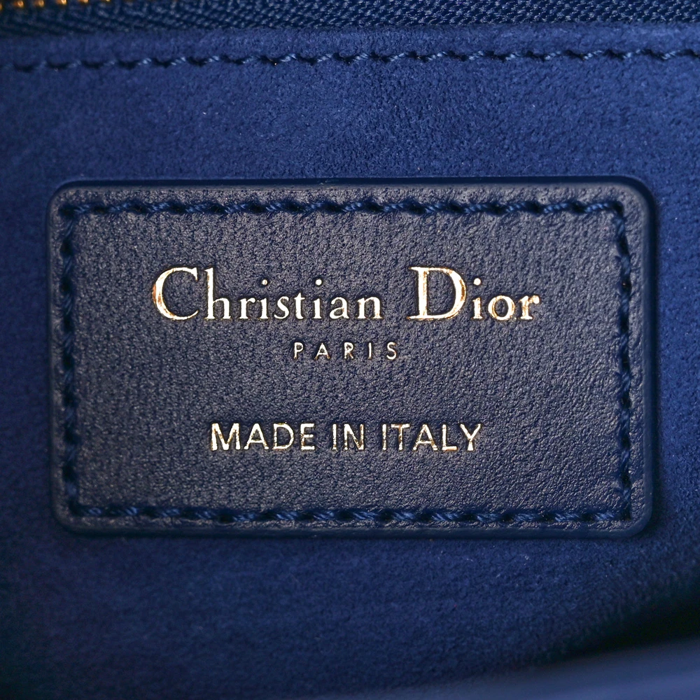 Close-up of the Dior charm and polished light gold-tone hardware on the blue Lady D!0r bag