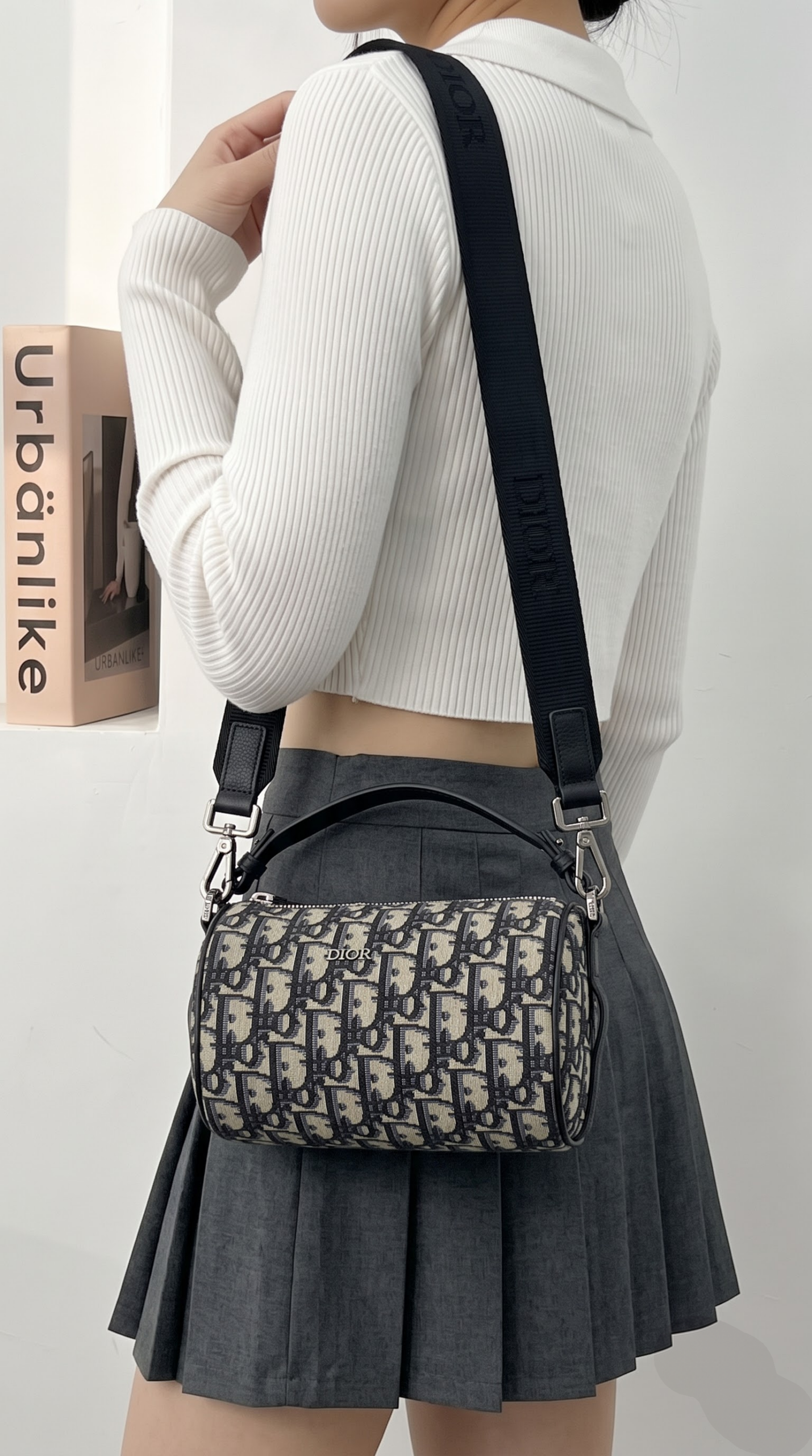 Model wearing the blue D!0r Mini Roller Messenger Bag crossbody with adjustable logo strap